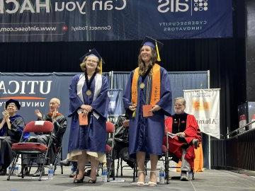 2024 Valedictorian Shayla Pominville and Salutatorian Sara Rachon stand on stage together at the 2024 Undergraduate Commencement ceremony.