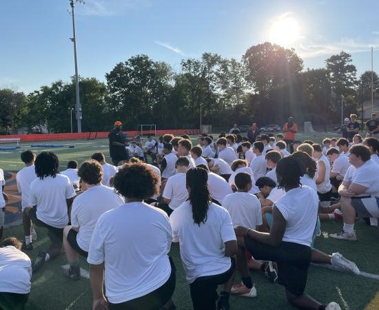 Players kneel on the field for A 呼叫 to Men Football Camp