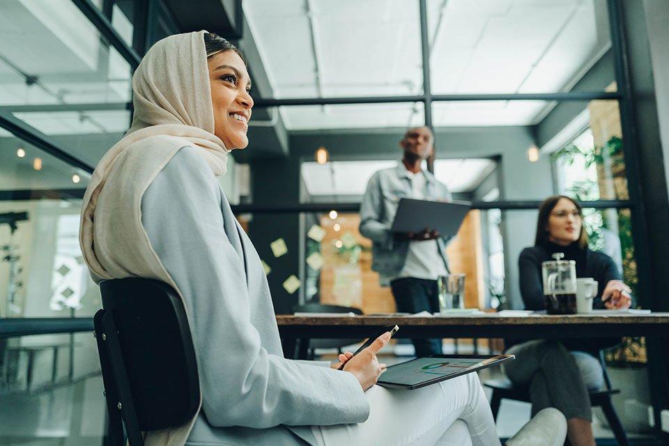 Woman smiling in a business meeting around a table with other professionals.